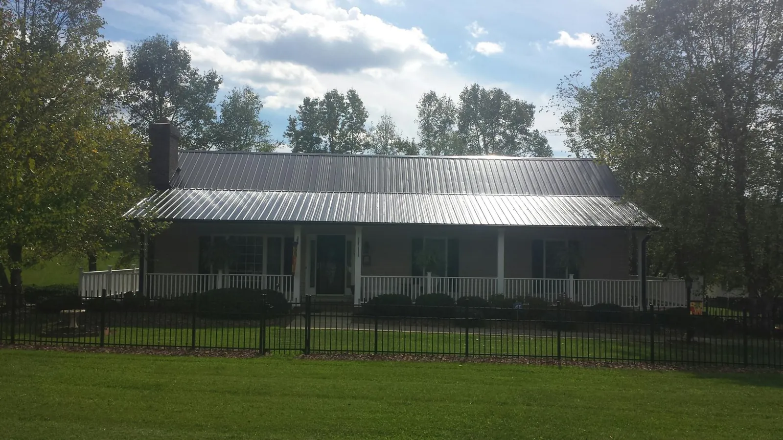 Gray metal roof on a brick ranch with a full width front porch — Gutter Guard Installation work by our crew in Franklinton