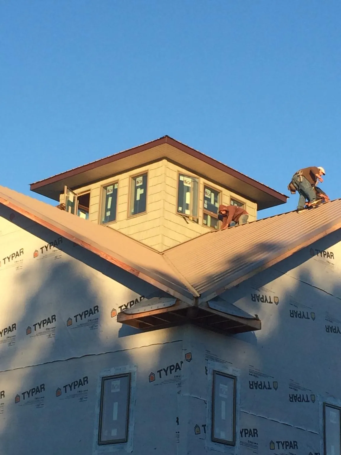 Roofers working around a rooftop cupola on a new metal roof at sunset — Roof Waterproofing in Franklinton by Roofing Brothers